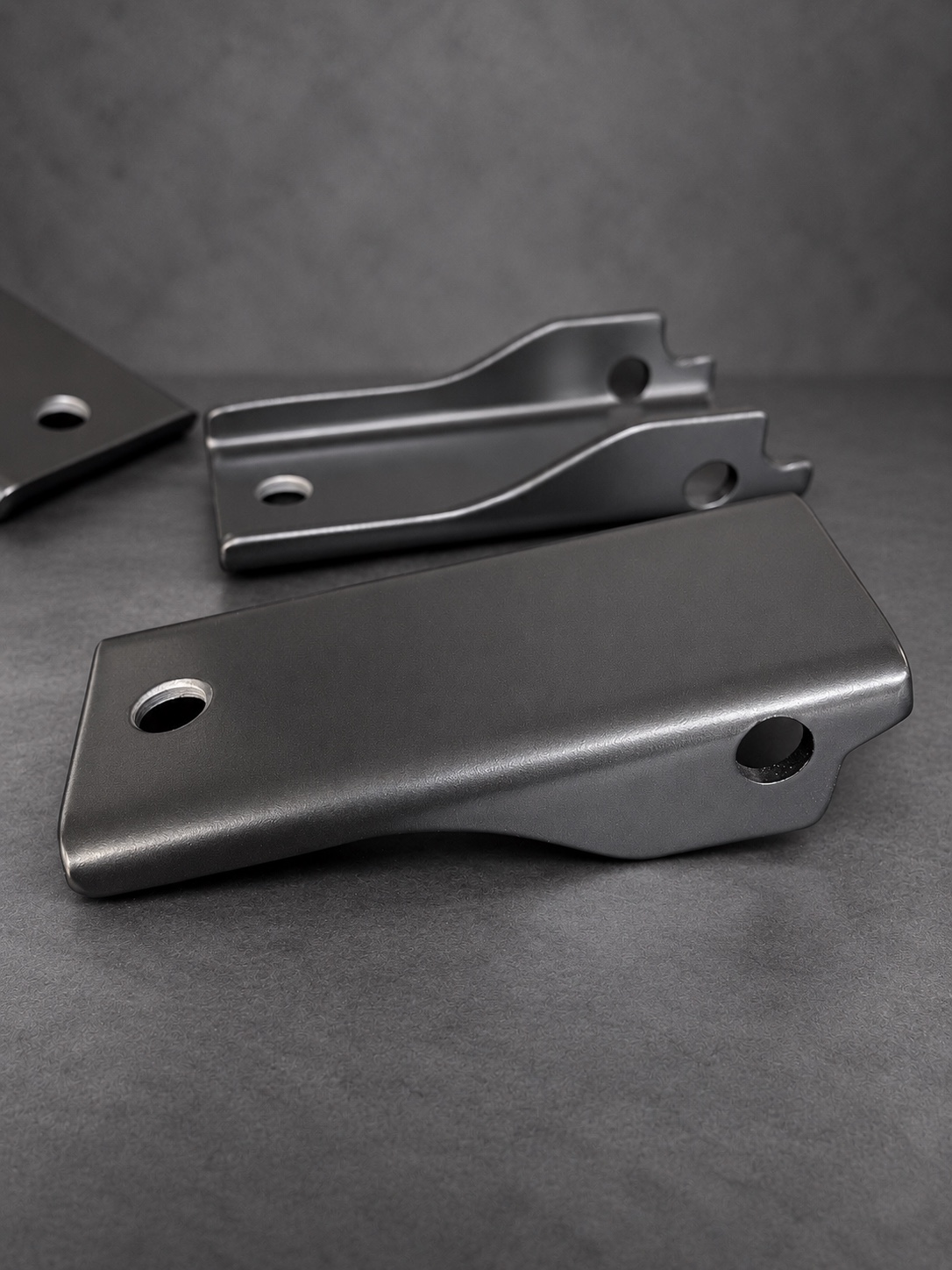 Close-up of black Cerakote E Series folded brackets showing surface texture and mounting holes