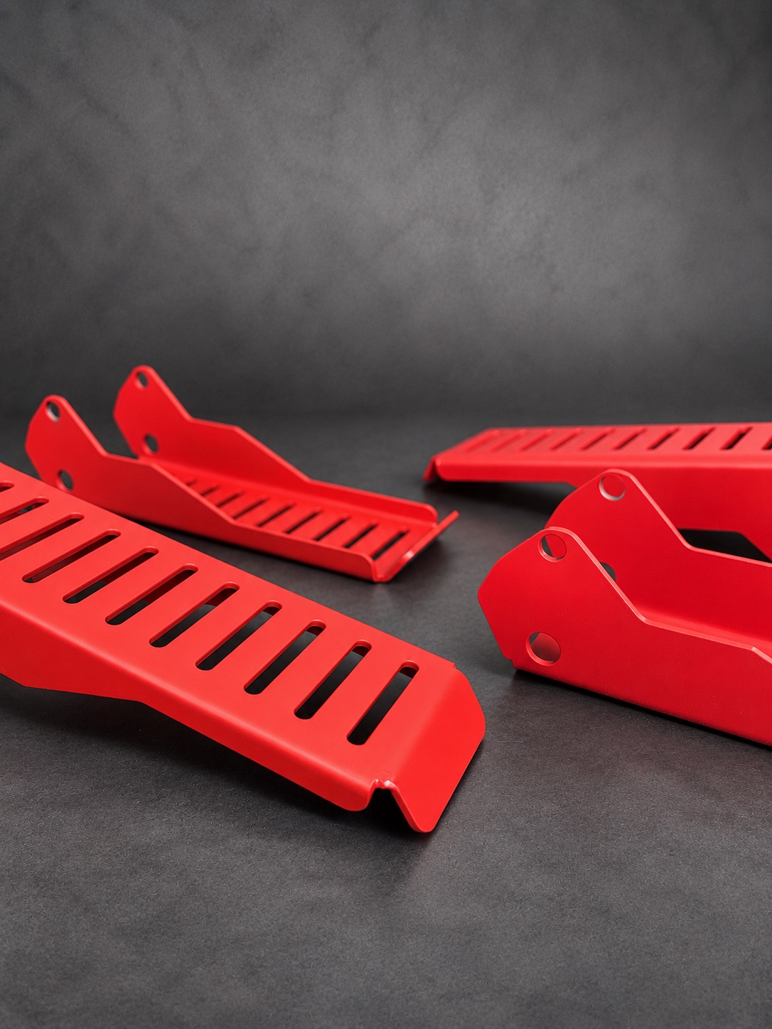Alternate view of red Cerakote E Series slotted brackets against a textured grey background