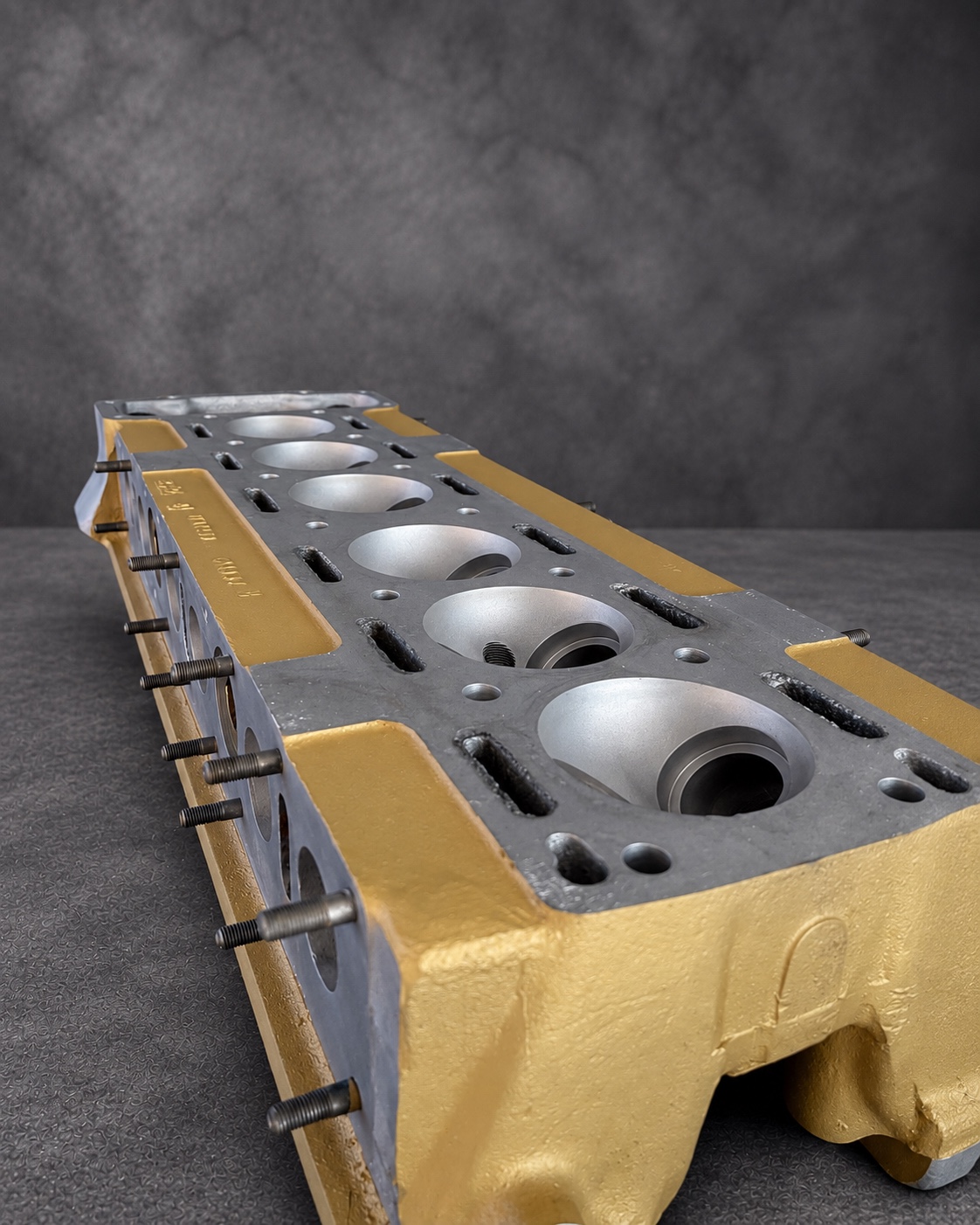 Gold Cerakote H Series cylinder head showing six combustion chambers and exposed alloy faces