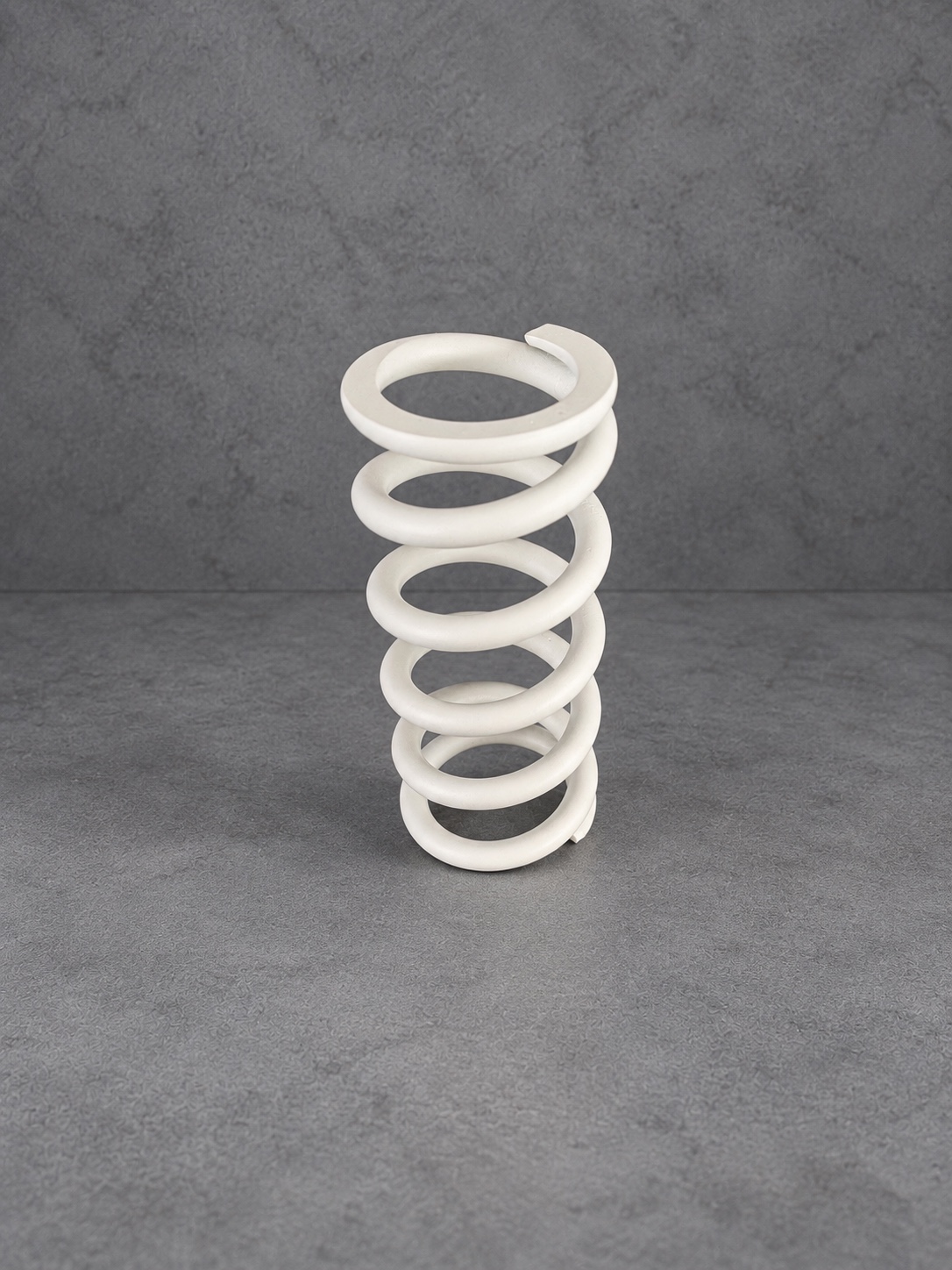White Cerakote H Series suspension spring standing upright against a grey background