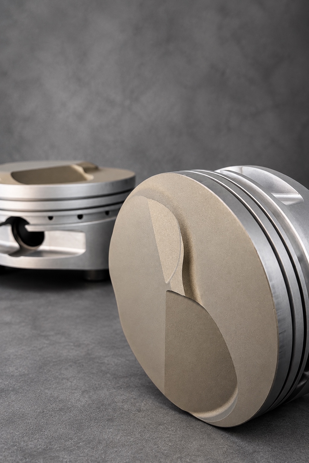 Close-up of ceramic-coated piston crowns with exposed alloy skirts and ring grooves
