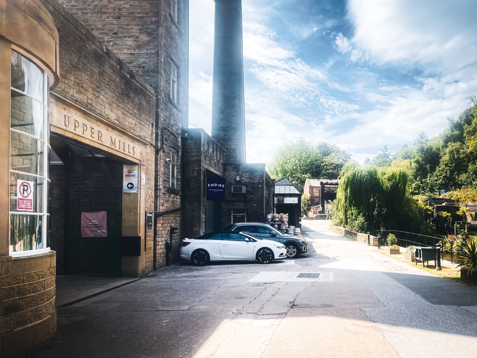 Upper Mills entrance and tall mill chimney beside Canal Side in Slaithwaite