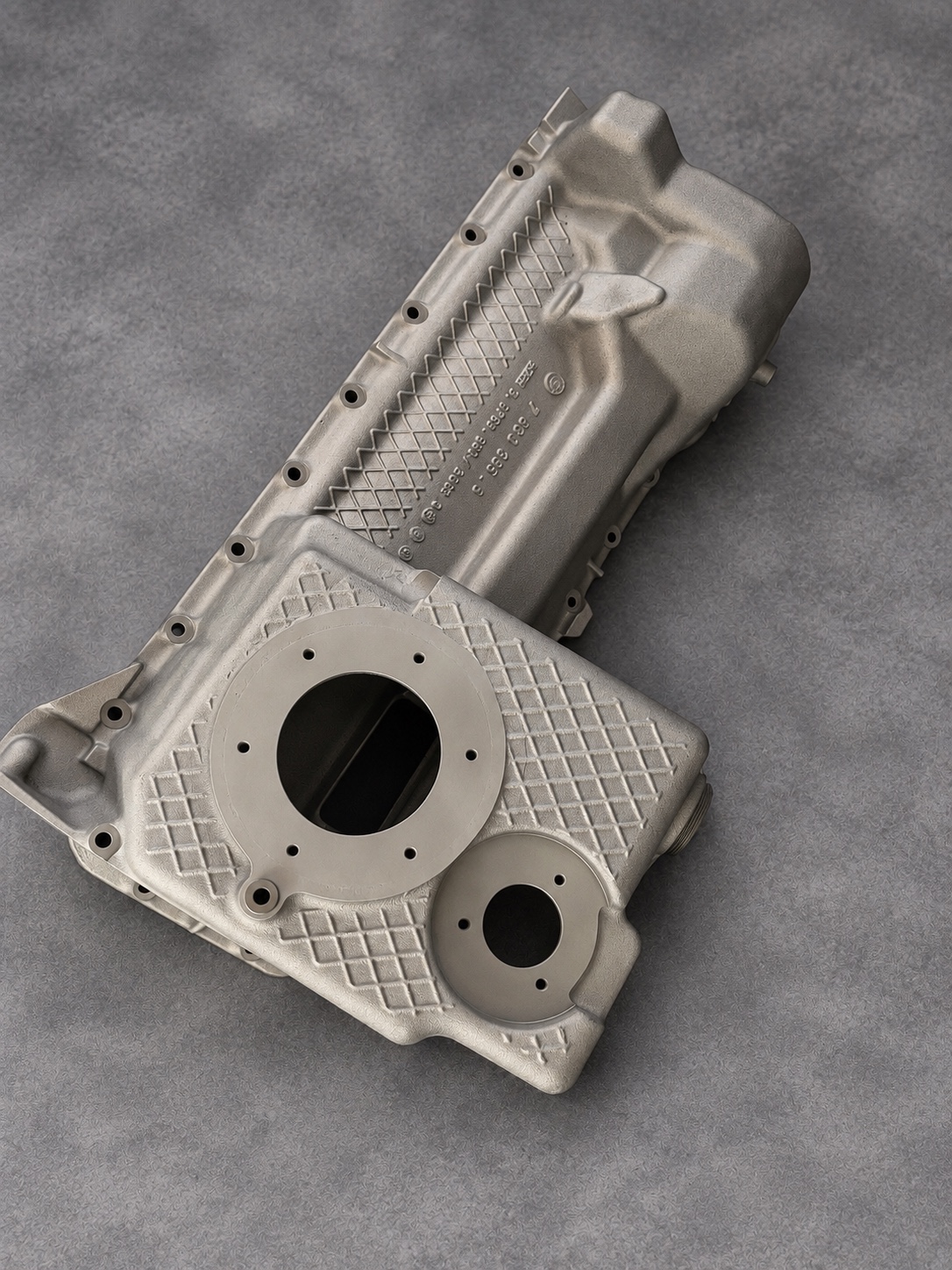 Overhead view of a vapour-blasted alloy sump showing machined openings and cross-hatched casting ribs