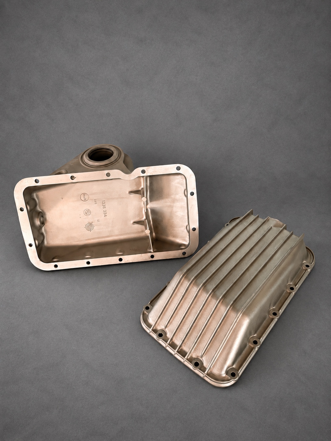 Two vapour-blasted alloy sumps showing interior and finned exterior surfaces