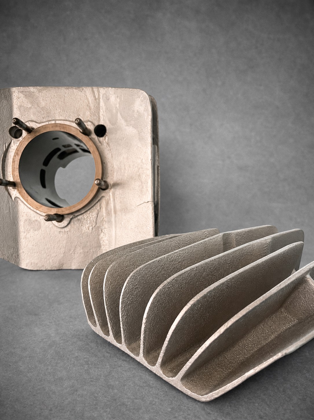 Vapour-blasted cylinder and separate finned cylinder head on a grey background