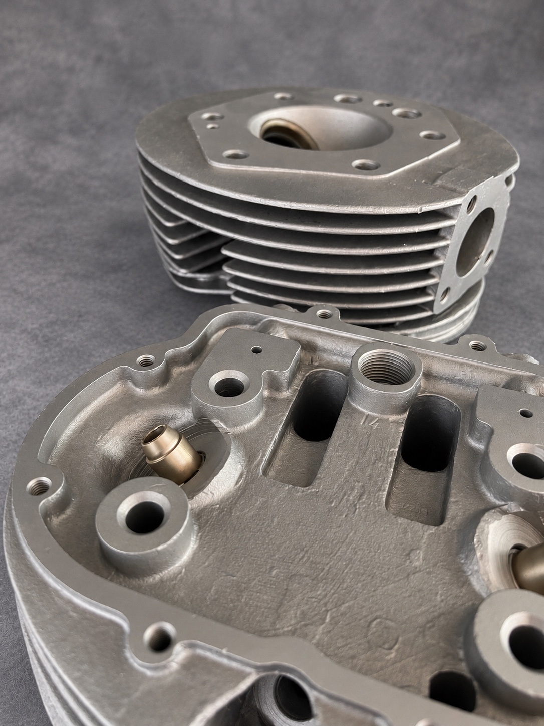 Close-up of vapour-blasted cylinder heads showing cast texture, threads and cooling fins