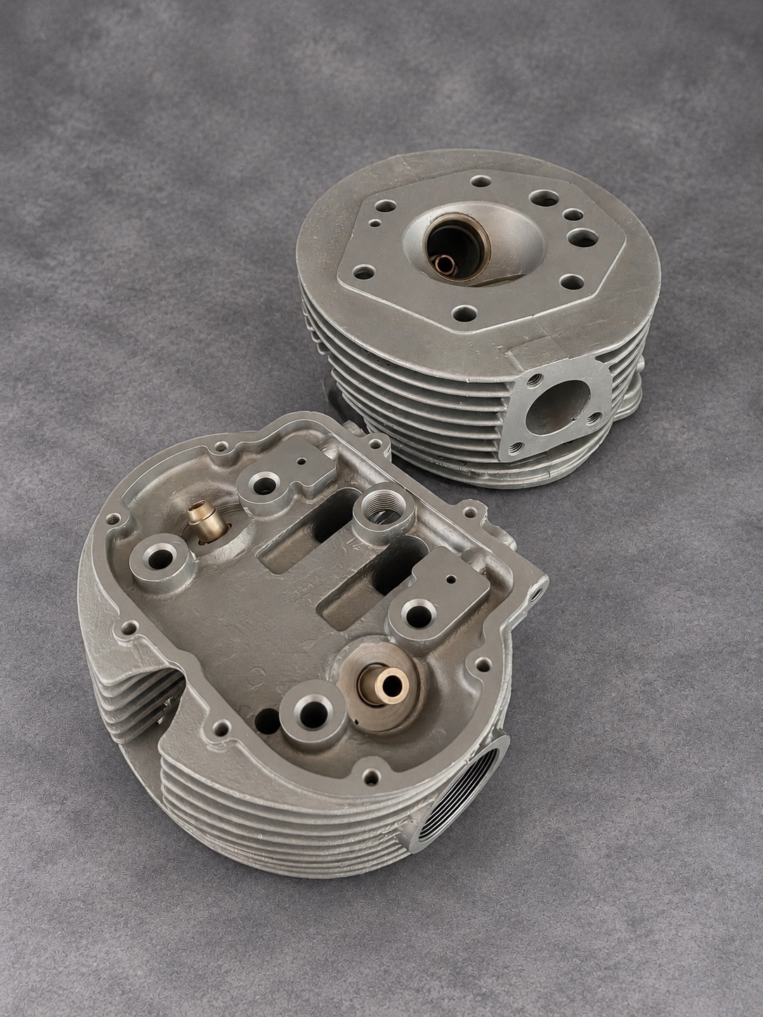 Pair of vapour-blasted finned cylinder heads showing valve guides, ports and combustion chamber