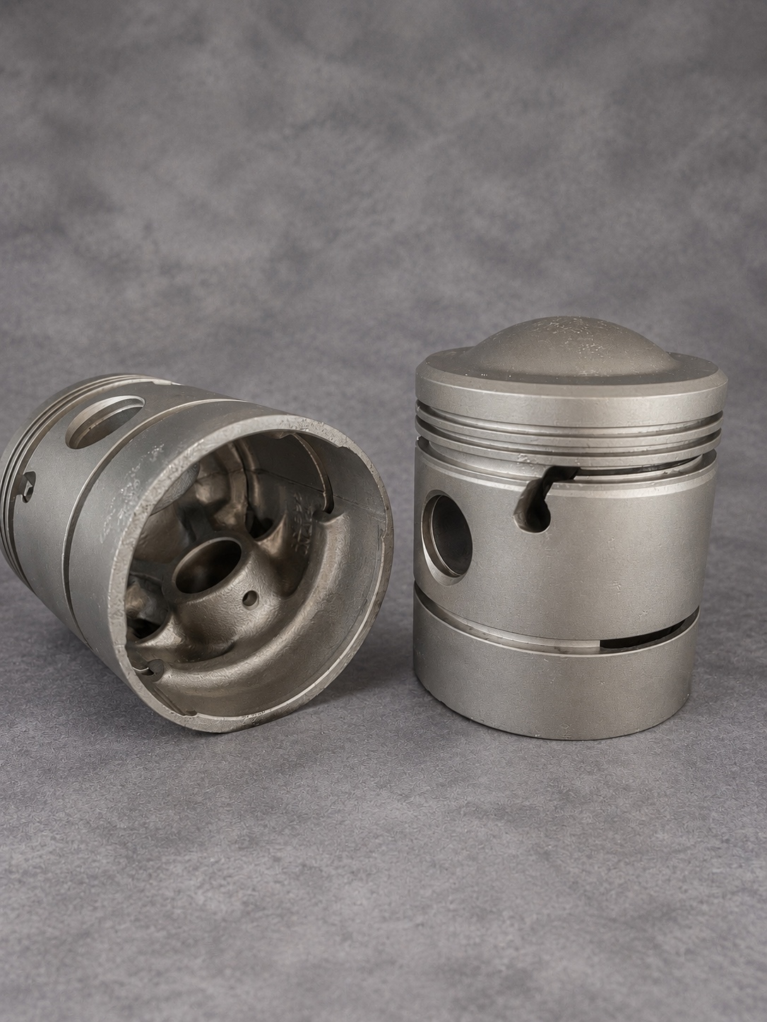 Vapour-blasted pistons showing the interior casting, gudgeon pin bore and ring grooves