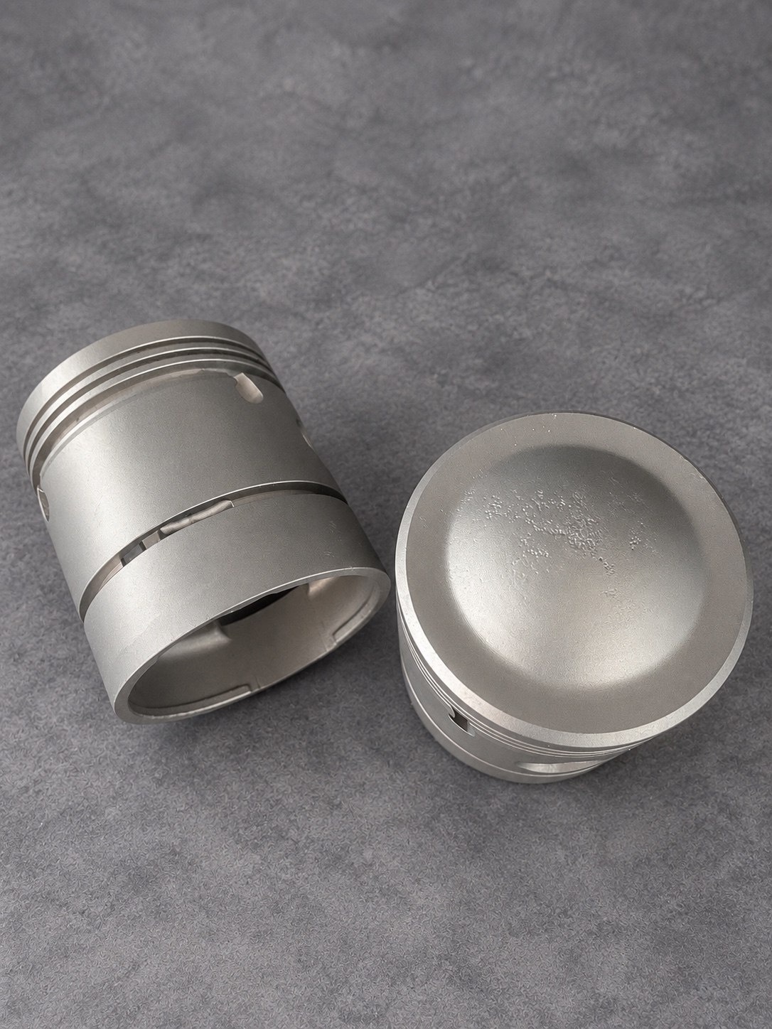 Overhead view of cleaned pistons showing a domed crown and skirt detail